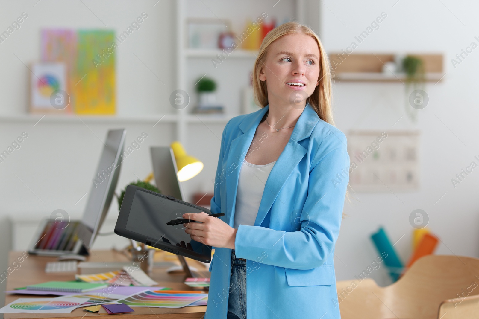 Photo of Beautiful young designer with tablet in office