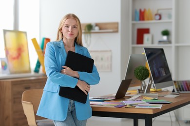 Beautiful young designer with tablet in office