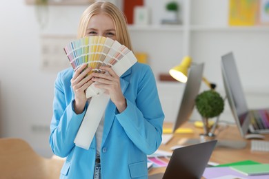 Photo of Young designer with color samples in office