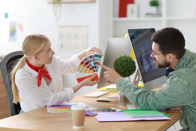 Designers with color samples working together at table in office