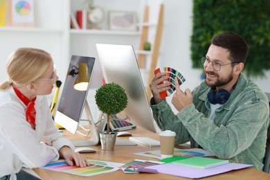 Designers with color samples working together at table in office