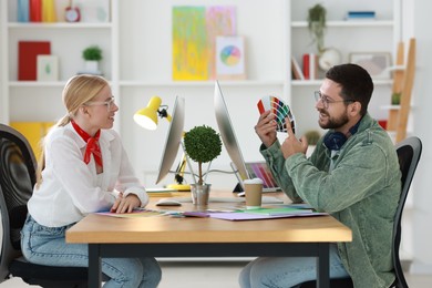 Photo of Designers with color samples working together at table in office