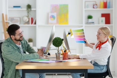 Designers with color palette working together at table in office