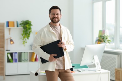 Smiling designer with tablet working in office