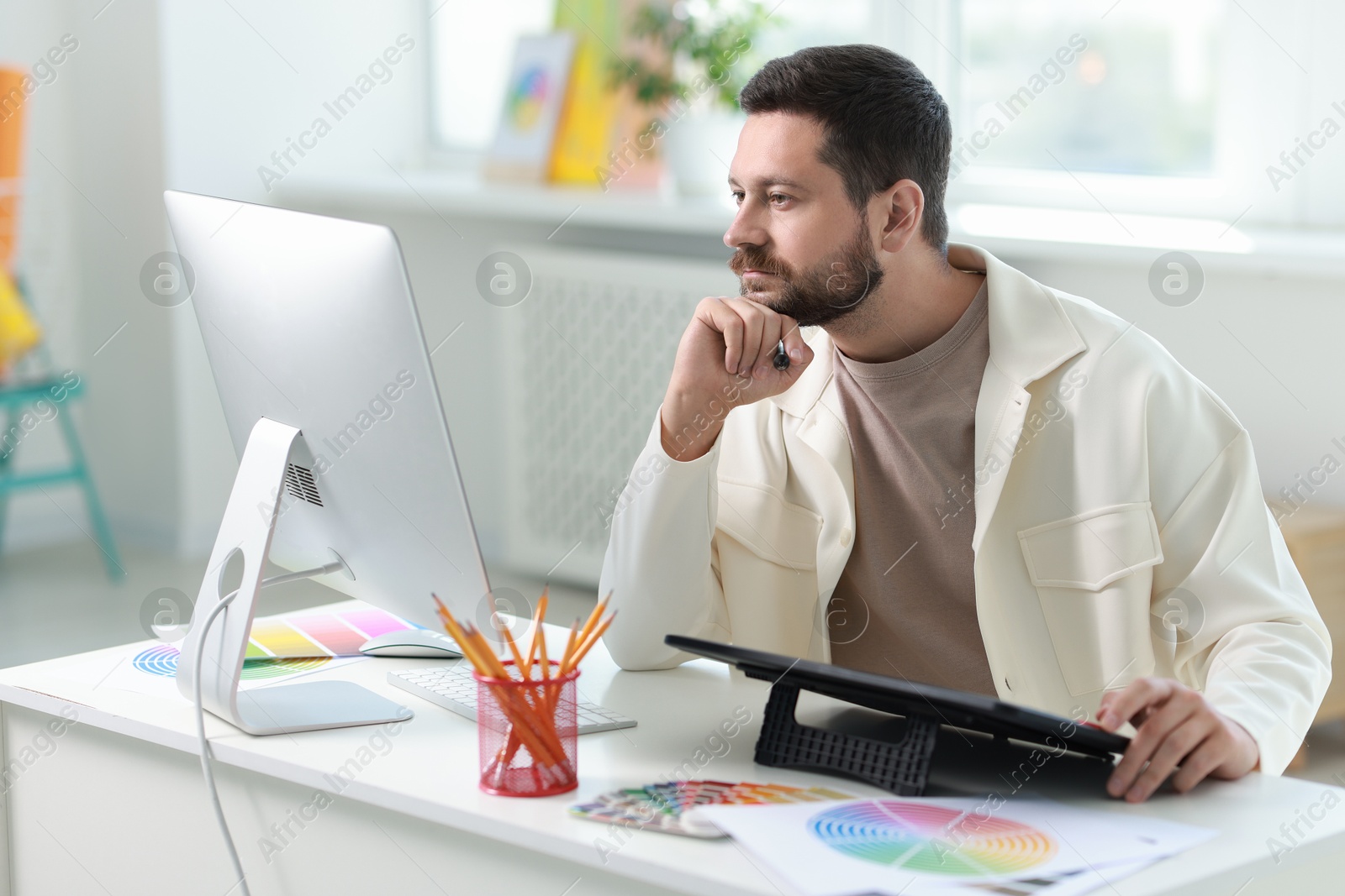 Photo of Designer working with tablet at table in office