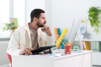 Photo of Designer working with tablet at table in office