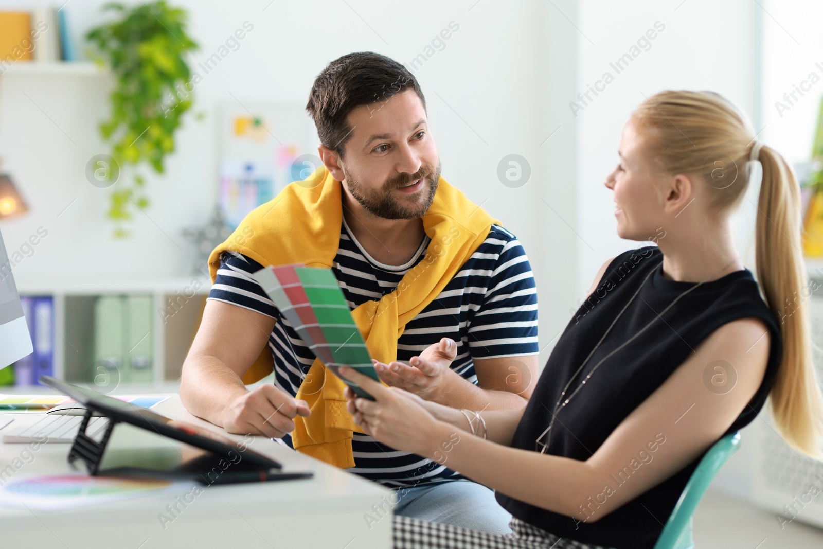 Photo of Designers with color samples working together at table in office