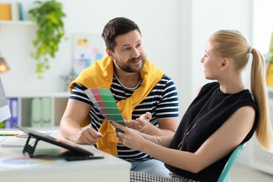 Designers with color samples working together at table in office