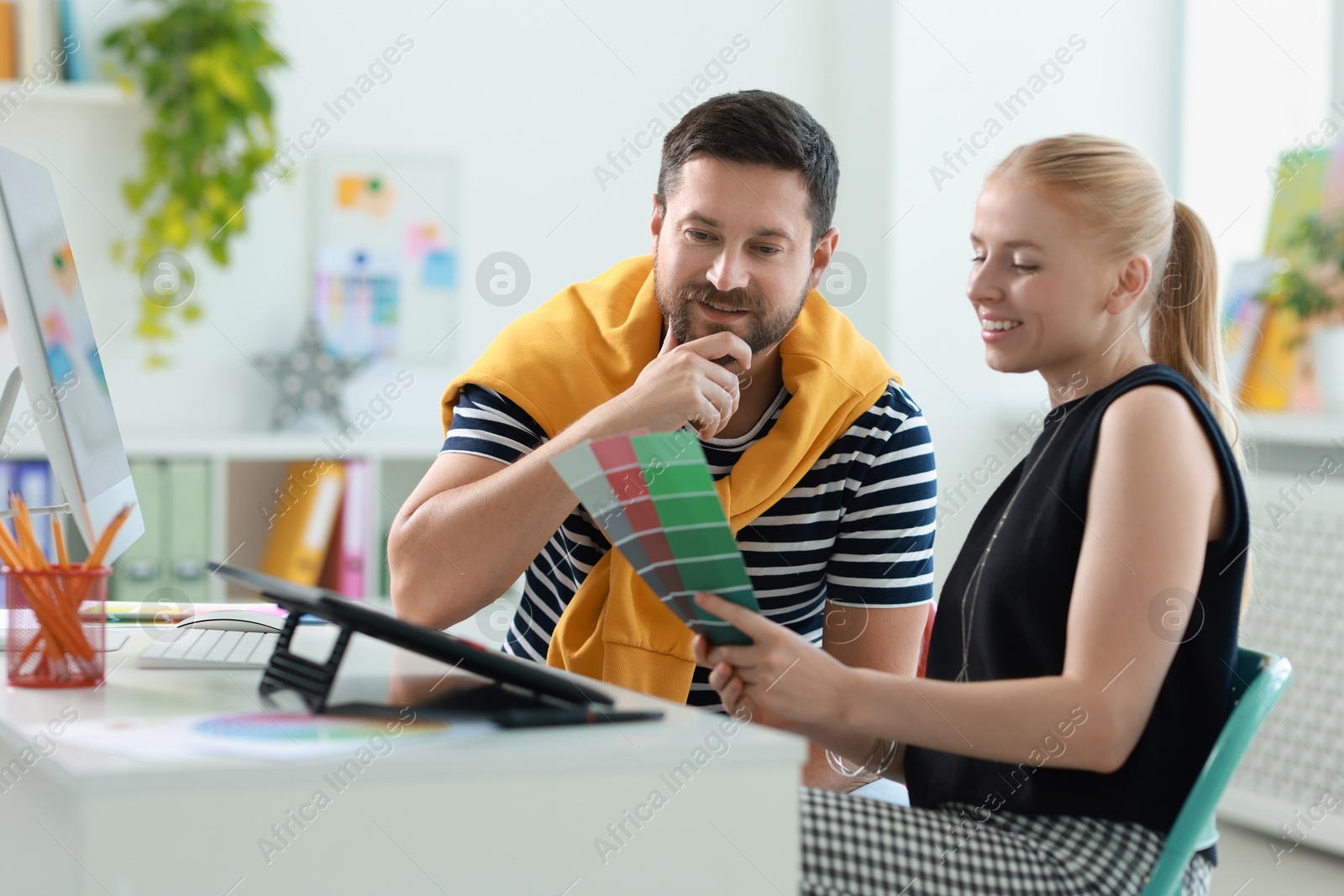 Photo of Designers with color samples working together at table in office