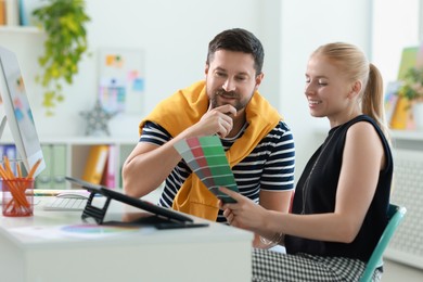 Photo of Designers with color samples working together at table in office