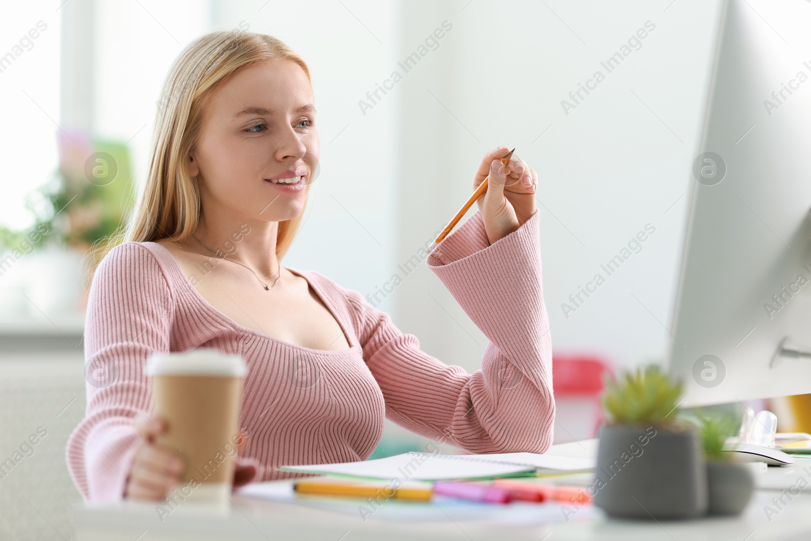 Photo of Designer with paper cup of drink working at table in office