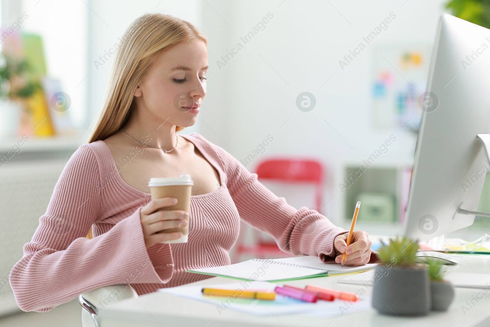 Photo of Designer with paper cup of drink working at table in office