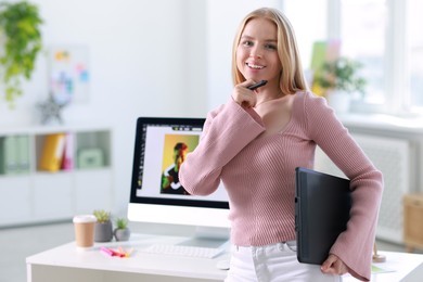 Beautiful young designer with tablet in office