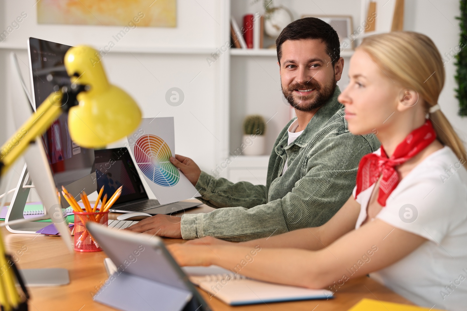 Photo of Designers working together at table in office, selective focus