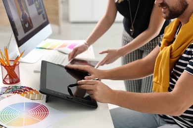 Photo of Designers working together with tablets at table in office, closeup