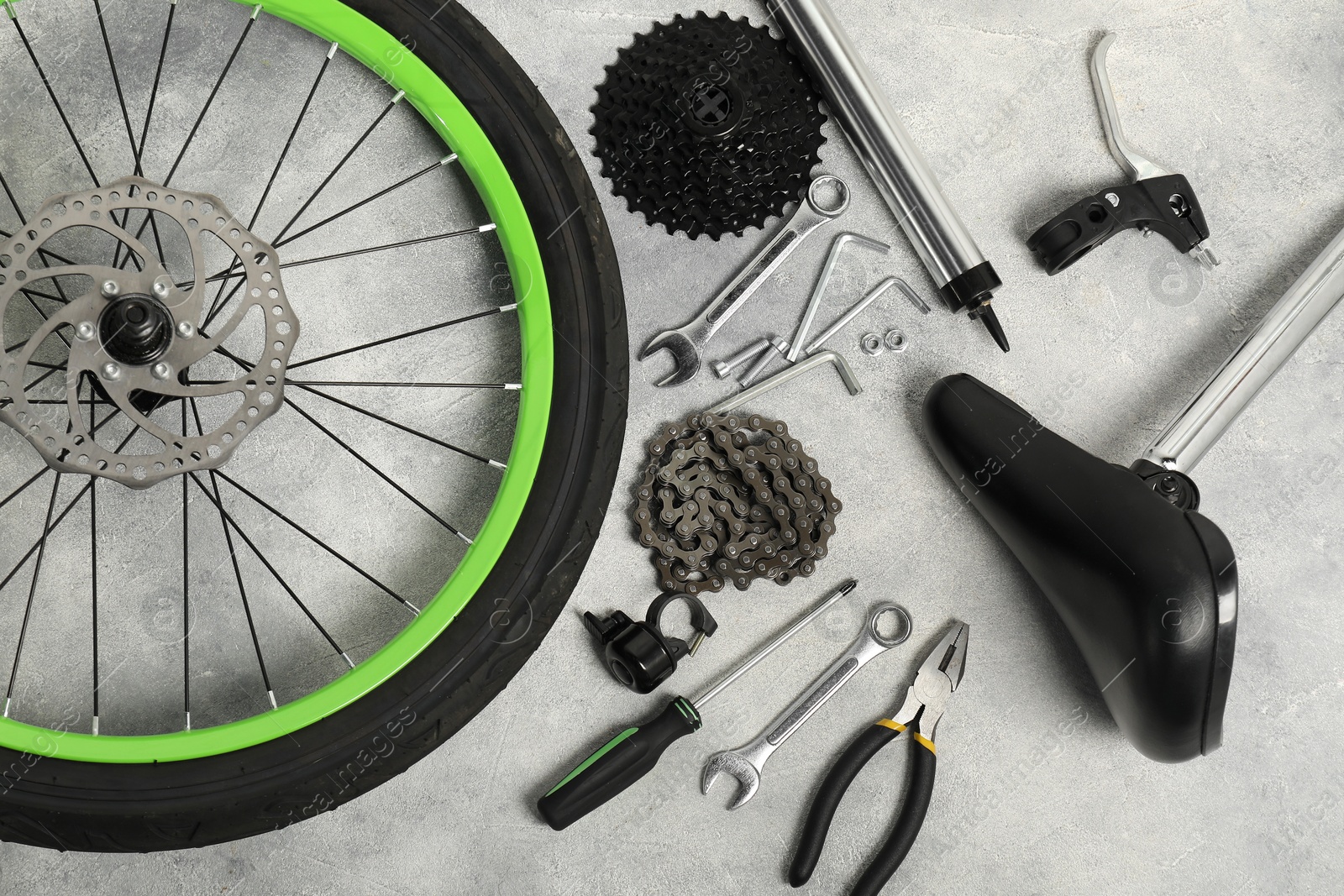 Photo of Parts of bicycle and tools on grey background, flat lay