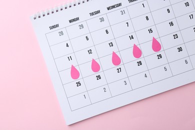 Photo of Menstruation. Calendar with marked dates on pink background, top view