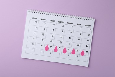 Photo of Menstruation. Calendar with marked dates on violet background, top view