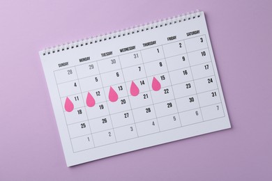 Photo of Menstruation. Calendar with marked dates on violet background, top view