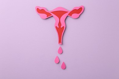 Photo of Menstruation. Paper uterus with drops on violet background, top view