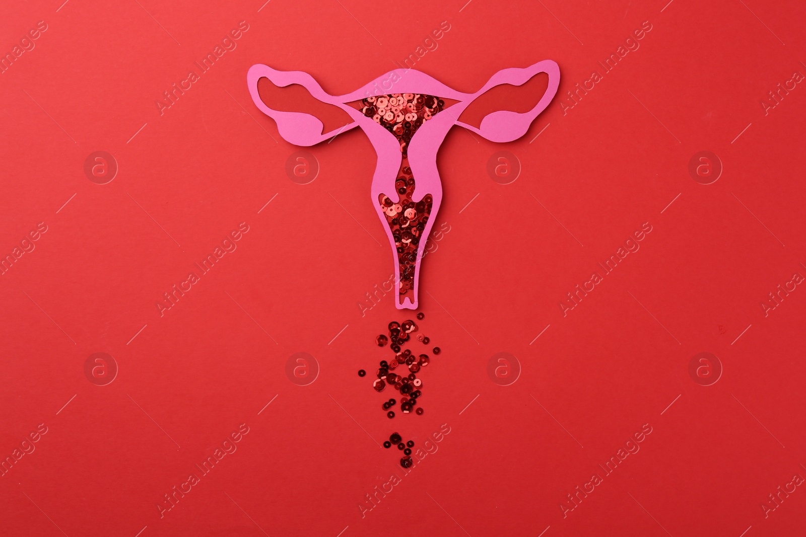 Photo of Menstruation. Paper uterus with sequins on red background, top view