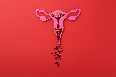 Menstruation. Paper uterus with sequins on red background, top view