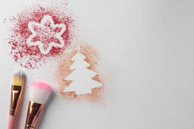 Photo of Christmas decorations made of powder and blush near makeup brushes on white background, flat lay. Space for text