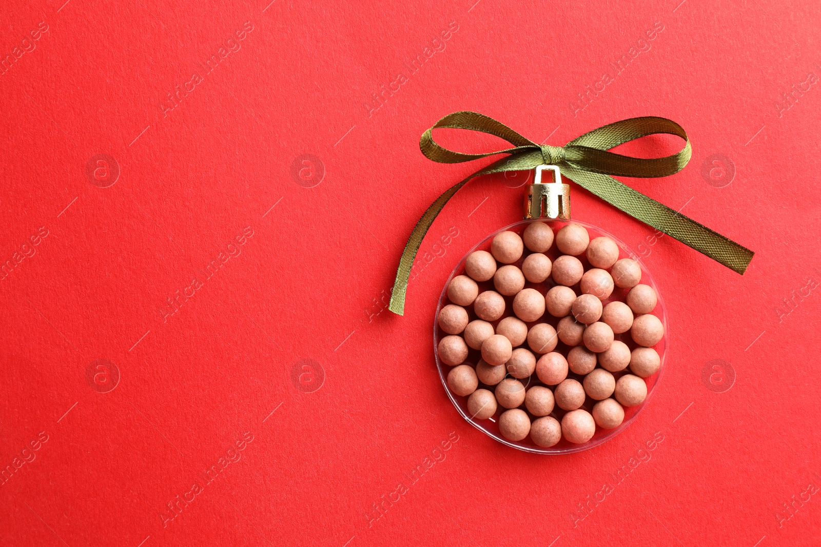 Photo of Christmas ball made with blush on red background, top view. Space for text