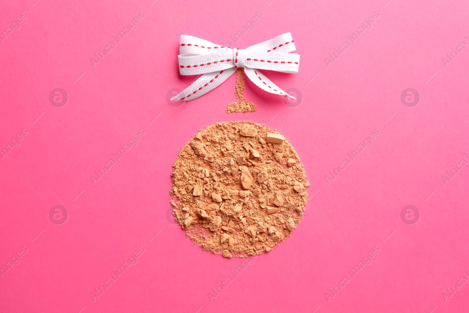 Photo of Christmas ball made with face powder on pink background, top view