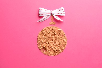 Photo of Christmas ball made with face powder on pink background, top view