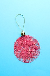 Photo of Christmas ball made with blush on light blue background, top view