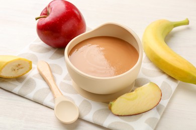 Photo of Delicious baby food in bowl and ingredients on white wooden table