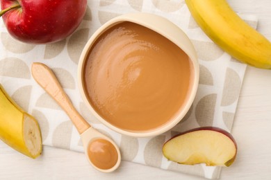 Photo of Delicious baby food in bowl and ingredients on white wooden table, flat lay