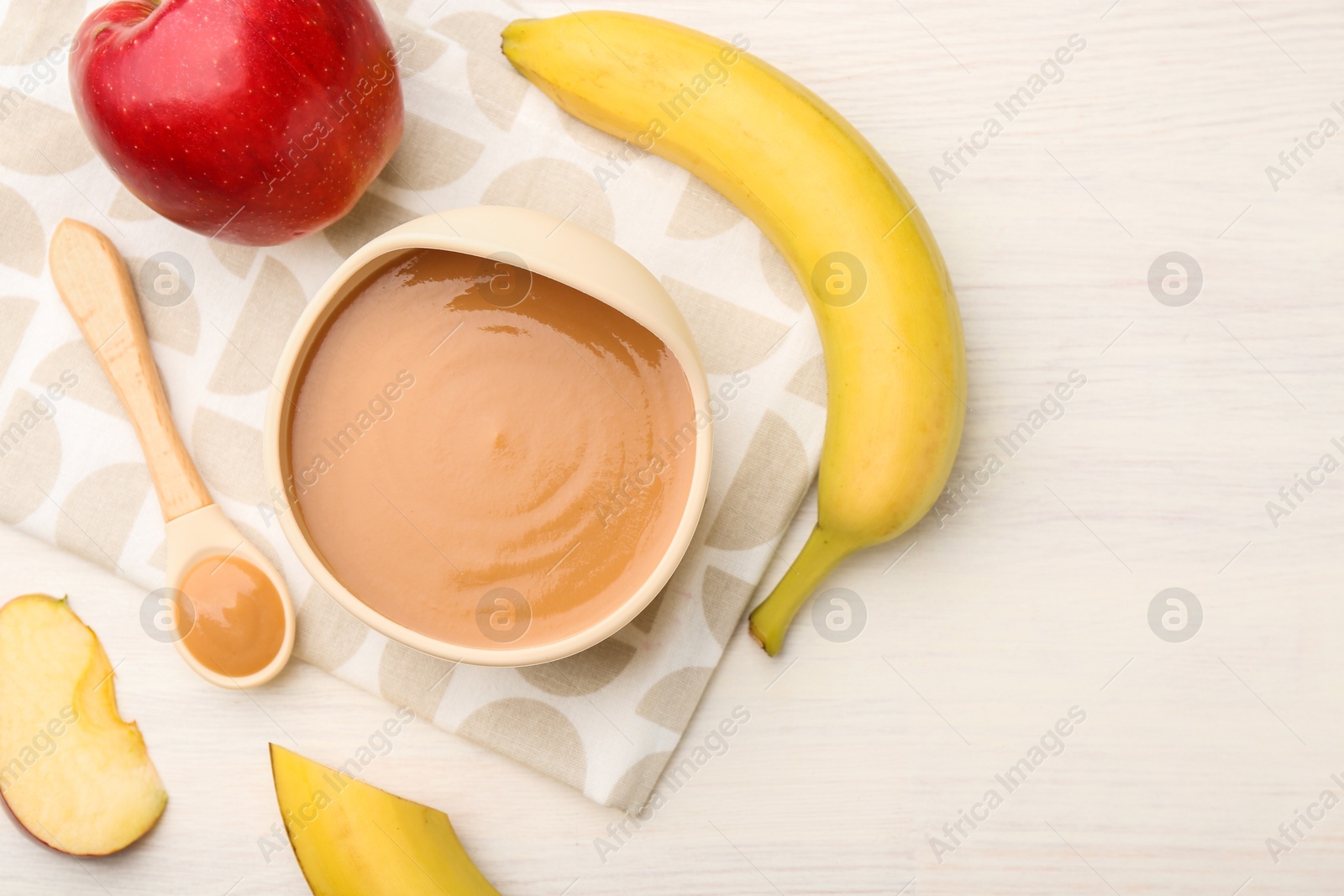 Photo of Delicious baby food in bowl and ingredients on white wooden table, flat lay