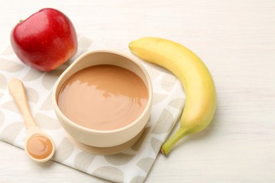 Photo of Delicious baby food in bowl and ingredients on white wooden table