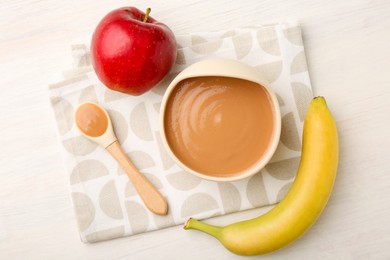 Photo of Delicious baby food in bowl and ingredients on white wooden table, flat lay