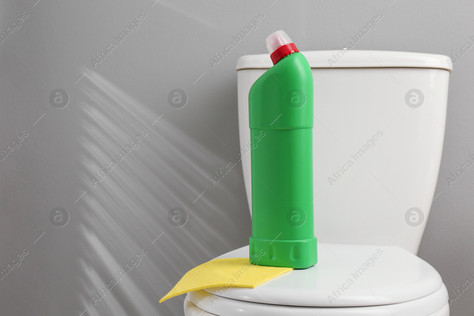 Photo of Detergent and rag on clean toilet in bathroom