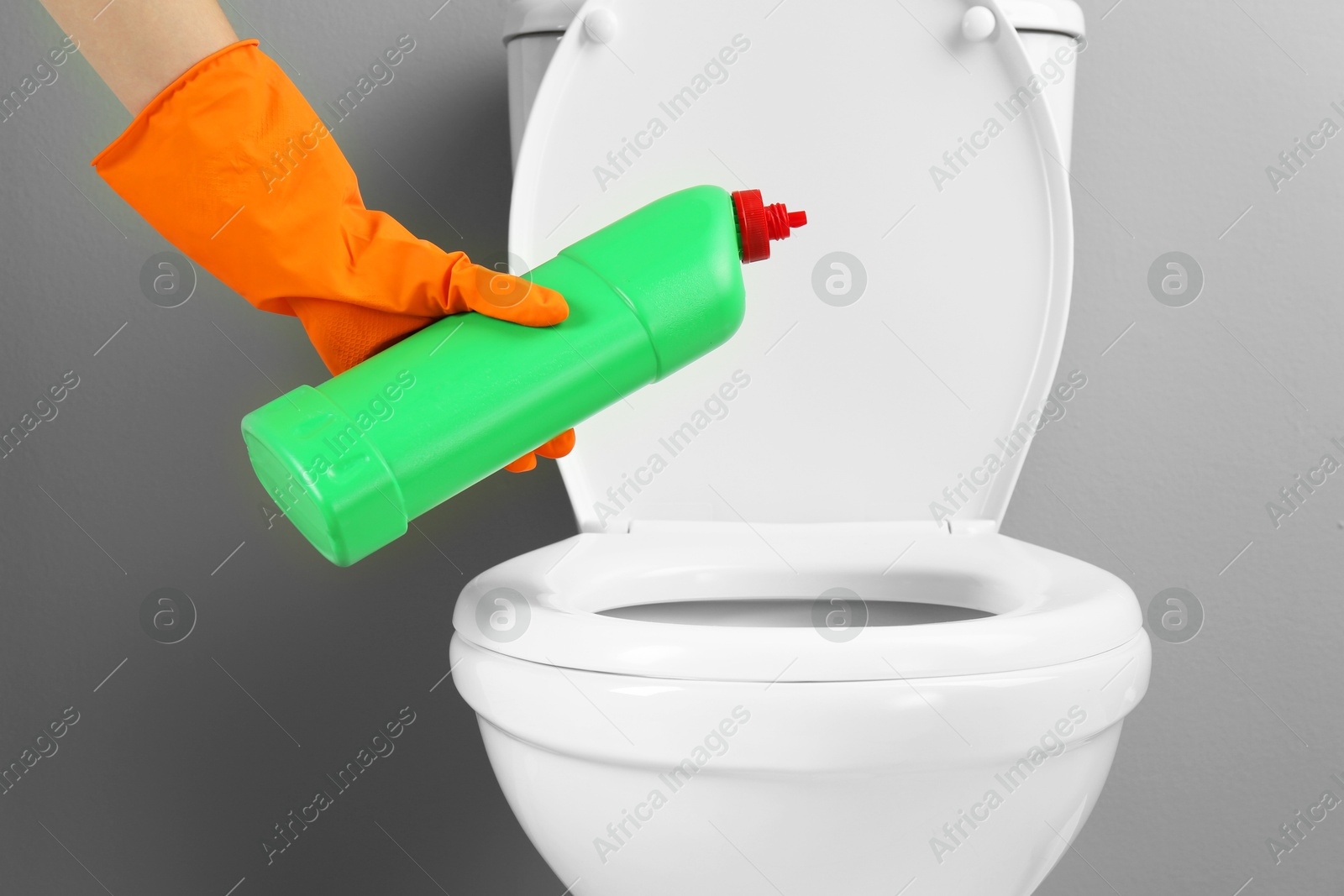 Photo of Woman cleaning toilet with detergent in bathroom, closeup