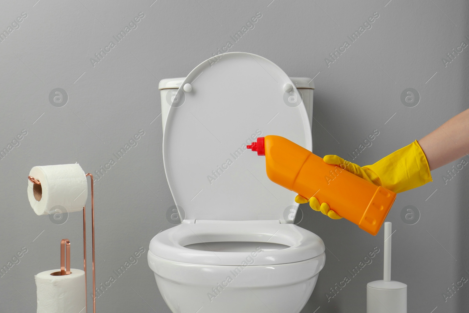 Photo of Woman cleaning toilet with detergent in bathroom, closeup