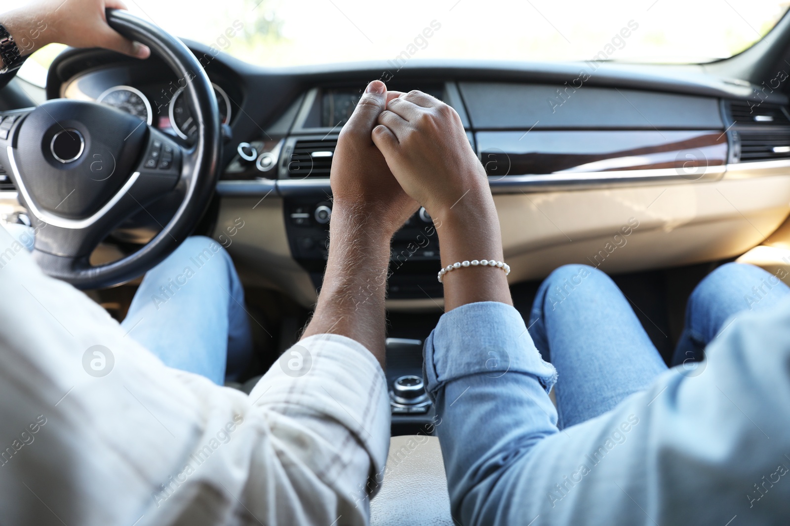 Photo of Lovely couple holding hands together while traveling by car, closeup