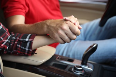 Photo of Lovely couple holding hands together while traveling by car, closeup