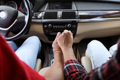 Photo of Lovely couple holding hands together while traveling by car, closeup