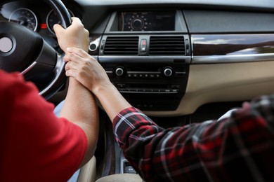 Lovely couple holding hands together while traveling by car, closeup