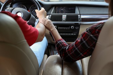 Photo of Lovely couple holding hands together while traveling by car, closeup