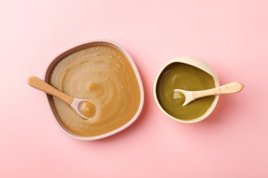 Photo of Delicious baby food and spoons in bowls on pink table, flat lay