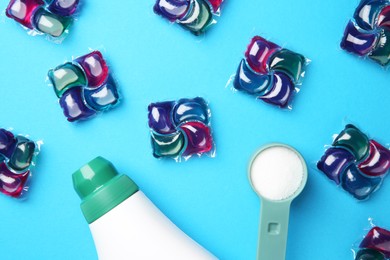 Photo of Bottle of fabric softener, laundry detergent pods and measuring scoop of washing powder on blue background, flat lay