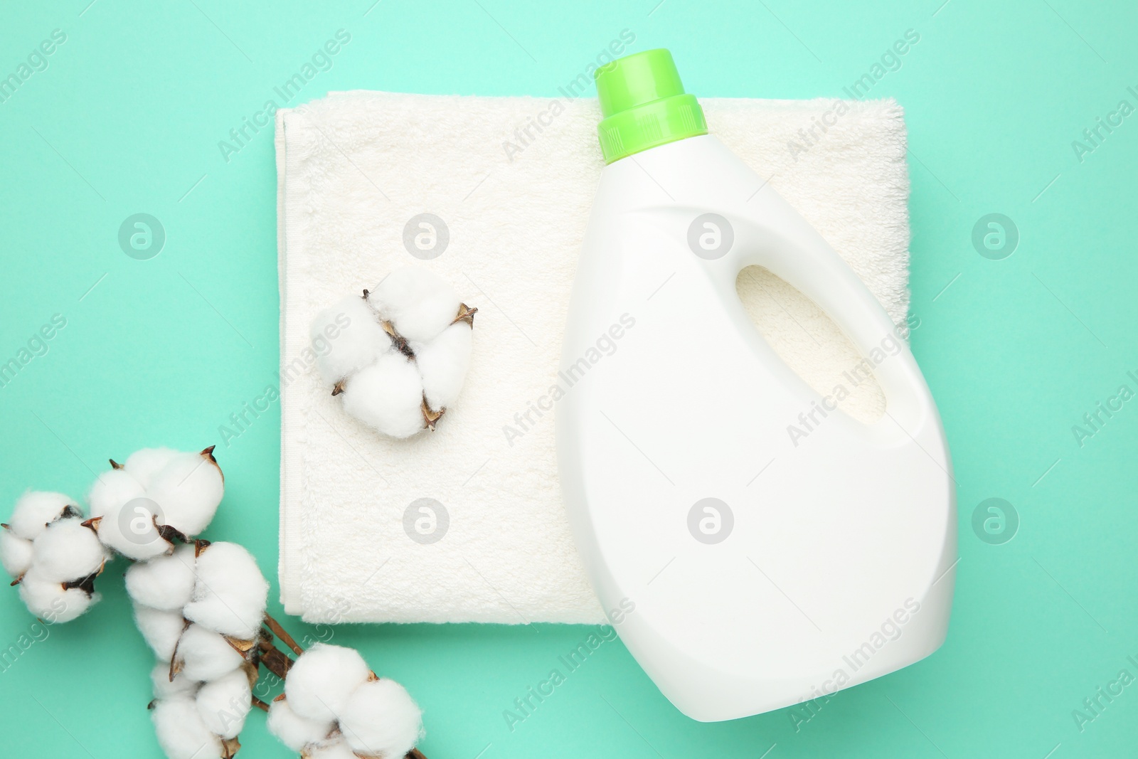 Photo of Bottle of laundry detergent, towel and cotton flowers on turquoise background, flat lay