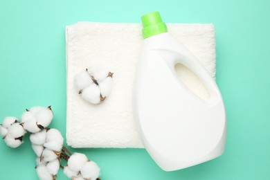 Photo of Bottle of laundry detergent, towel and cotton flowers on turquoise background, flat lay