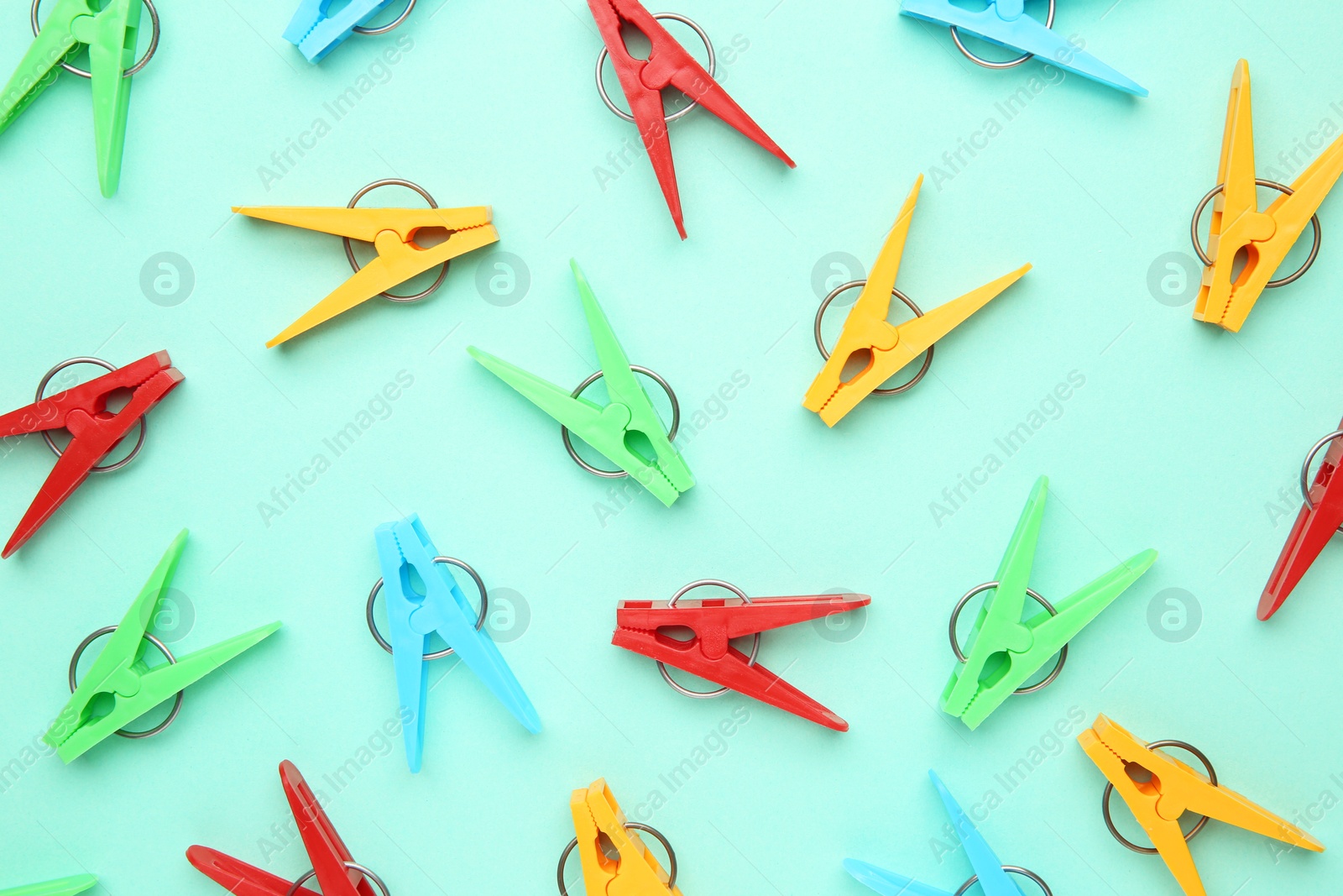 Photo of Many colorful clothespins on turquoise background, flat lay