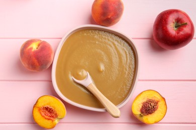 Photo of Delicious baby food with spoon in bowl and fresh ingredients on pink wooden table, flat lay